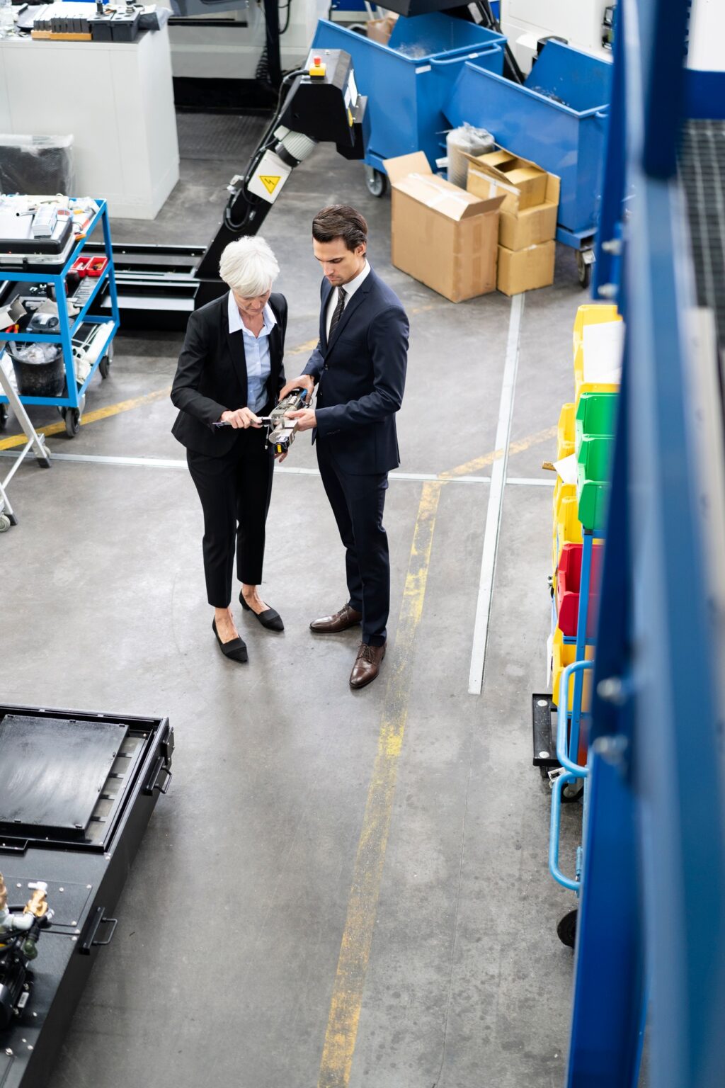 Businessman and senior businesswoman examining workpiece in a factory